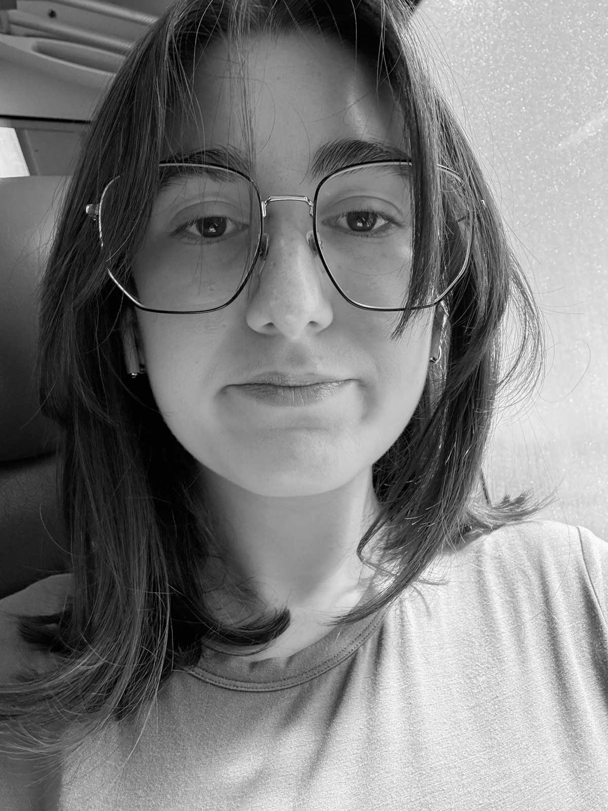 Black-and-white portrait of Madeline Heller, wearing round wire-framed glasses.